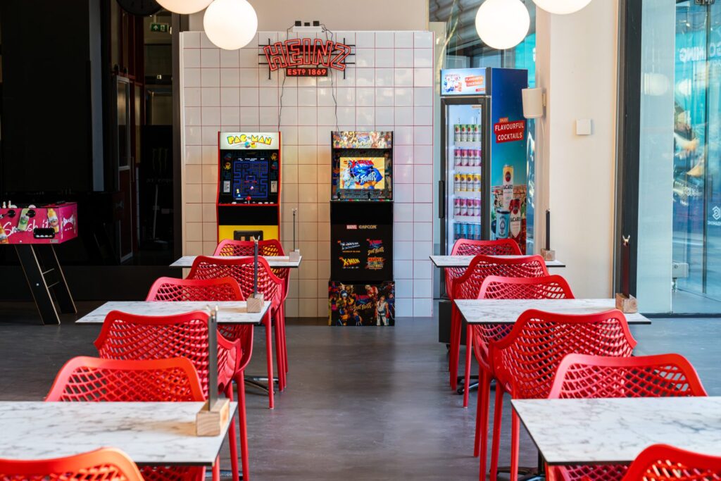 Interieur van Smash Burgers aan het Schouwburgplein in Rotterdam met rode stoelen en arcadekasten